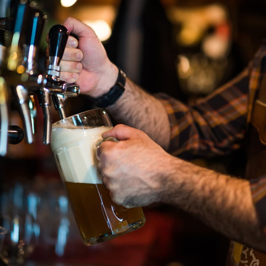A person is pouring beer from a tap into a glass mug.